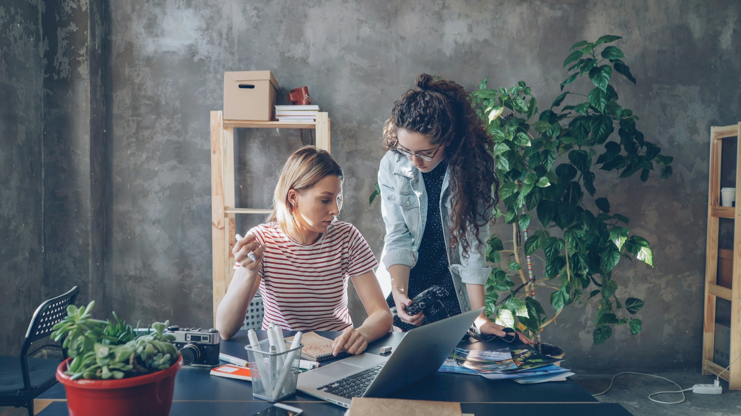 Two colleagues reviewing work together at a laptop